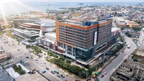 Un hotel moderno con varios pisos, un letrero llamativo y vistas de la ciudad.