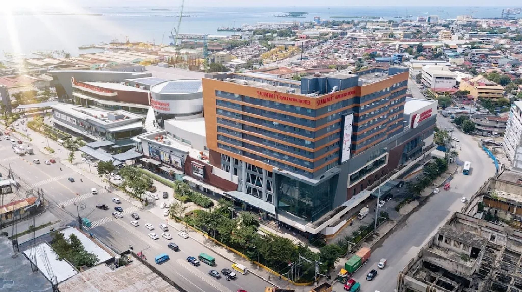 A modern hotel with multiple floors, a prominent sign, and a view of the surrounding cityscape.