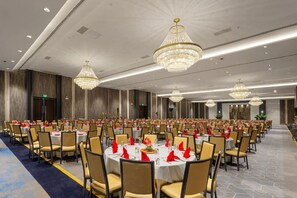 Un salón de banquetes con mesas redondas, sillas y candelabros.