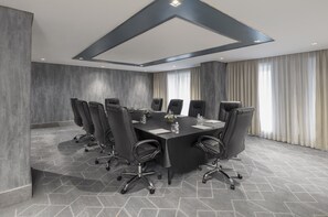 A conference room with a large rectangular table, multiple chairs, and a modern ceiling design.