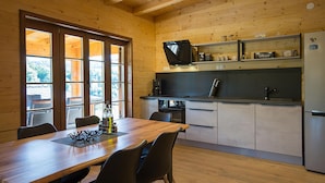 A modern kitchen with wooden walls, a dining table with chairs, a refrigerator, and a television on a shelf. - Cozy home in Donje Taboriste with WiFi (Donje Taboriste)
