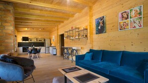 A cozy log cabin interior with a blue sofa, a dining area, and a kitchen. - Cozy home in Donje Taboriste with WiFi (Donje Taboriste)