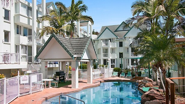 Un área de piscina con jacuzzi, sillas de descanso y palmeras.