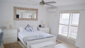 Un dormitorio con cama, mesitas de noche, un espejo y una ventana con persianas.