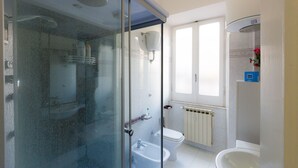 A modern bathroom with a glass shower enclosure, a toilet, and a sink. - Accogliente (Roma)
