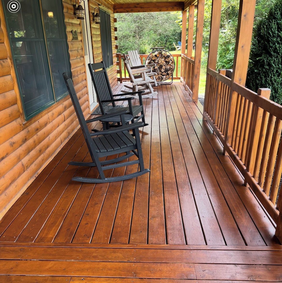 A wooden deck with rocking chairs and a fire pit.