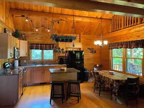 L’intérieur d’une cabane comprend une cuisine, un coin repas et une grande fenêtre donnant sur le paysage extérieur.