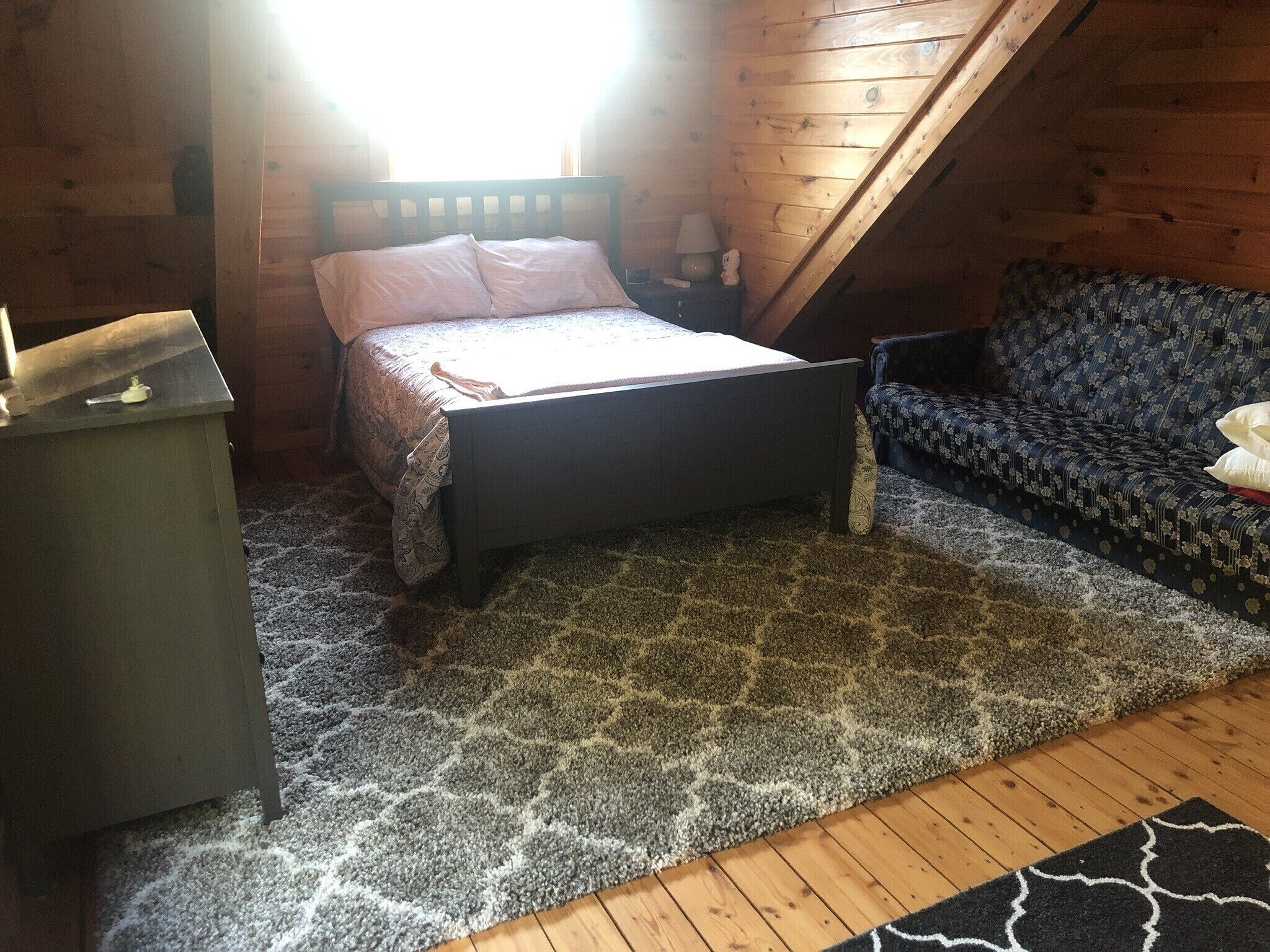 Une chambre à coucher avec un lit, une commode, un canapé à motifs et un plafond en bois.