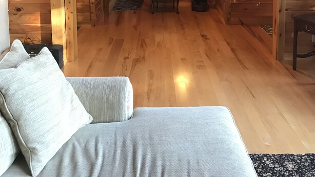 Puinen mökki sisältä, siellä on sänky, tuoli, pieni pöytä ja portaat, jotka johtavat ylemmälle tasolle.