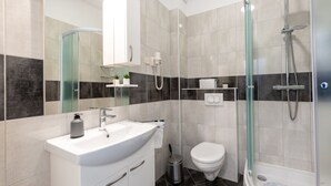 Une salle de bain moderne avec un lavabo blanc, une douche à parois de verre et des toilettes.