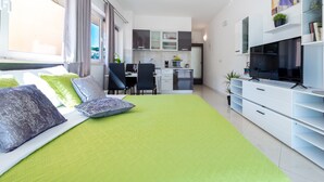 Un appartement moderne avec un espace de vie comprenant un canapé, une table à manger et une cuisine en arrière-plan.