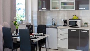 Une cuisine moderne avec un coin repas, comprenant une fenêtre, des placards, un évier, un four à micro-ondes et une machine à café.