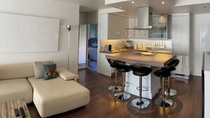 A modern kitchen with a central island, bar stools, and a dining area with a sofa. - Apartment center Saint-tropez (Saint-Tropez)