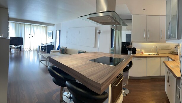 A modern kitchen with a wooden island, black bar stools, and white cabinetry. - Apartment center Saint-tropez (Saint-Tropez)