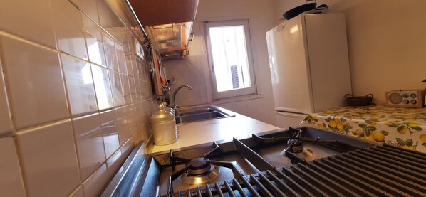 A compact kitchen with a gas stove, a sink, and a window providing natural light. - Detached villa with a large terrace and ocean view—200 m from the ocean (Baja Sardinia)