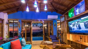 Un salon chaleureux avec un canapé bleu, une table basse en bois et un téléviseur diffusant une scène de cascade.