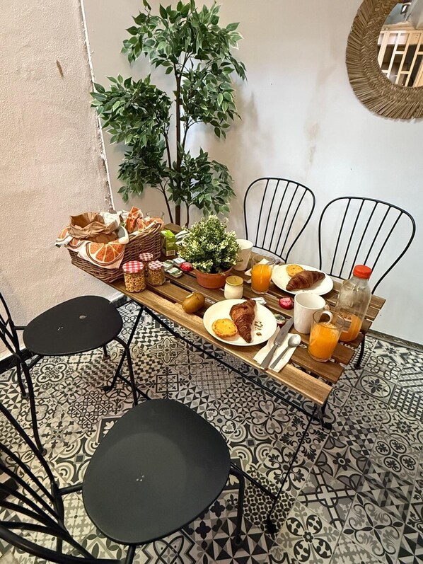A breakfast setup with a wooden table, two chairs, a potted plant, and a tiled floor.