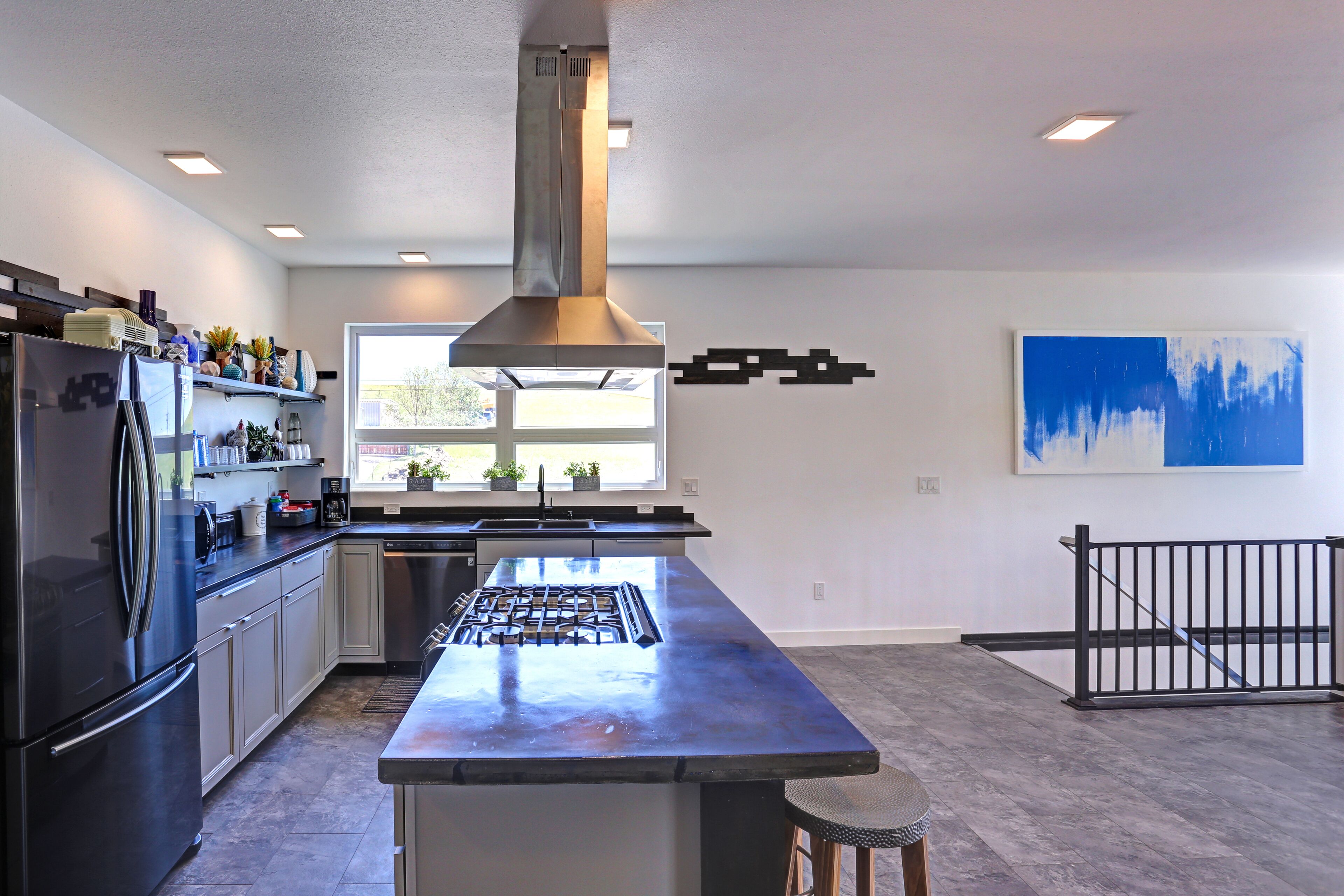 Una cocina moderna con una isla central, electrodomésticos de acero inoxidable y un amplio ventanal que proporciona luz natural.