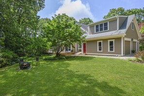 A two-story house with a red door, a covered porch, and a well-maintained lawn.