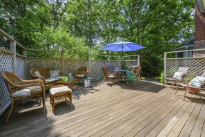 A wooden deck with wicker furniture, a table, and chairs.