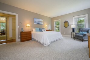 A bedroom with a bed, a dresser, a chair, and two windows.