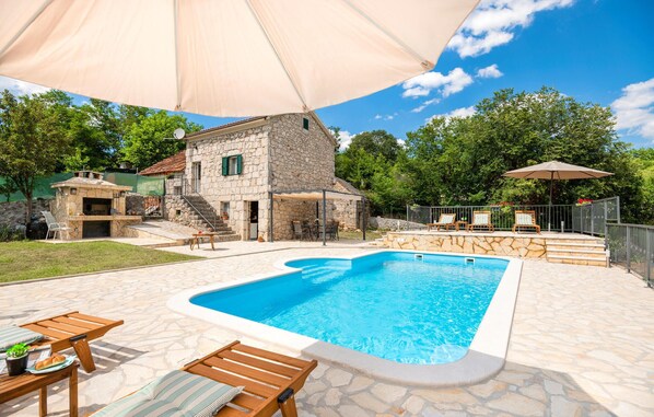 Relax by the pool surrounded by lush trees and a cozy fireplace.