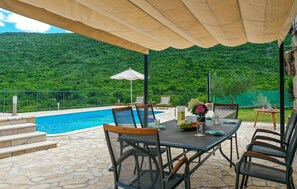 Relax by the pool surrounded by a lush hillside and enjoy the serene atmosphere.