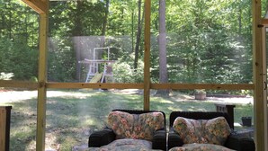 Eine überdachte Terrasse mit Korbmöbeln und Blick auf einen Spielplatz.
