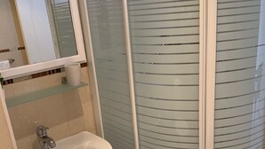 Ein Badezimmer mit Waschbecken, Spiegel und einer Duschkabine aus Glas.