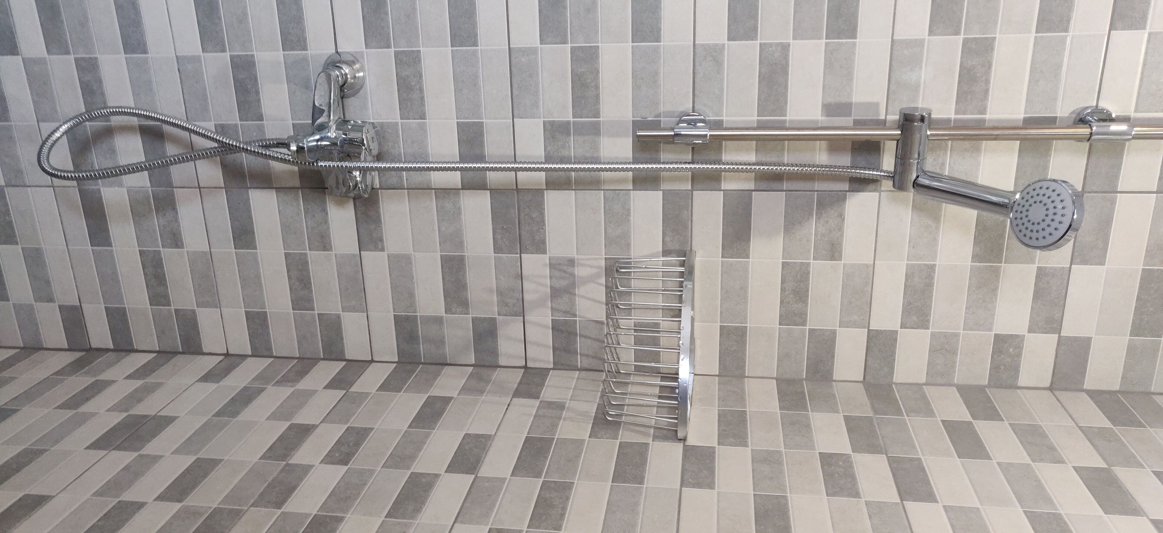 A shower with a handheld showerhead, a fixed showerhead, and a handheld shower hose.