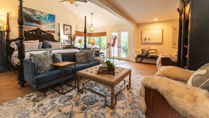 A spacious living room with a large bed, a blue sofa, a coffee table, and a fireplace.