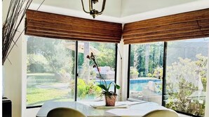 A dining area with a table and chairs, large windows, and a view of a garden.