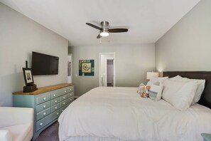 Une chambre à coucher avec un lit, une commode, un téléviseur et un ventilateur de plafond.