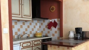 A compact kitchen with a sink, stove, and coffee maker.