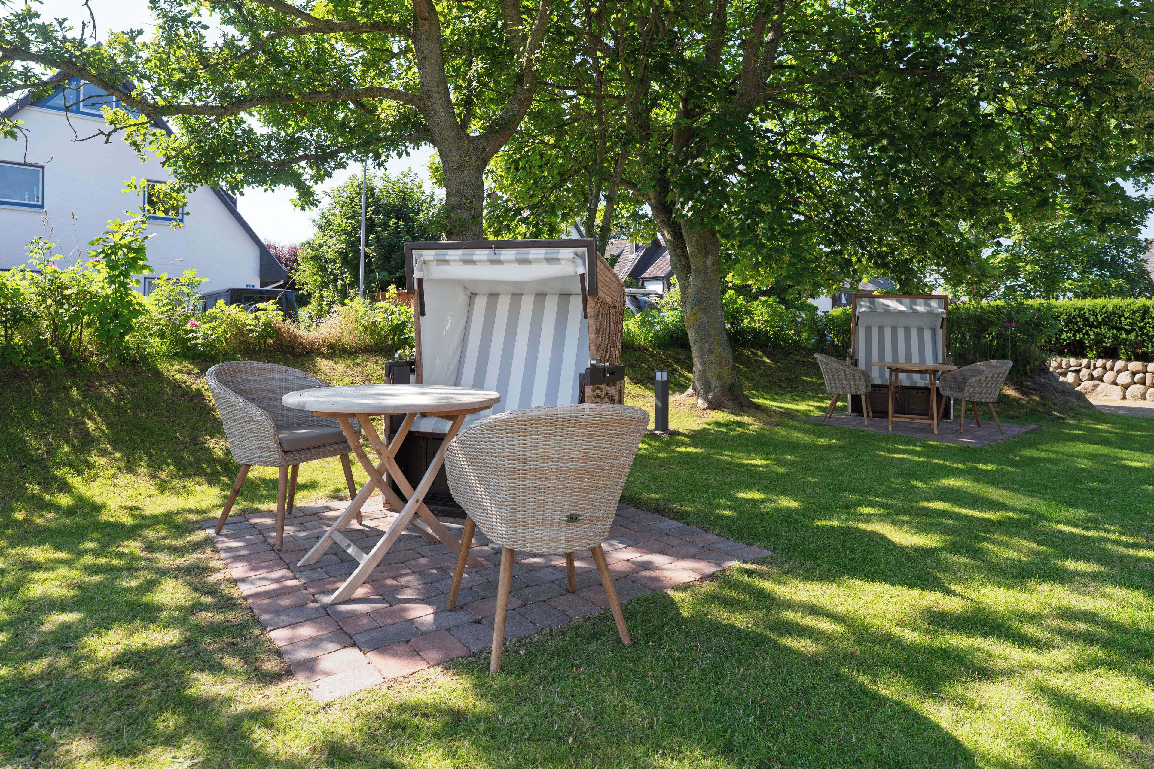 An outdoor patio area with wicker furniture, a striped umbrella, and a brick pathway.