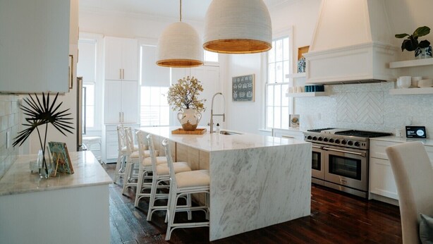 A modern kitchen with a central island, pendant lights, and a large stove.