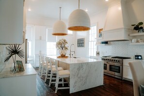 Une cuisine moderne dotée d’un îlot central, de luminaires suspendus et d’une grande cuisinière.
