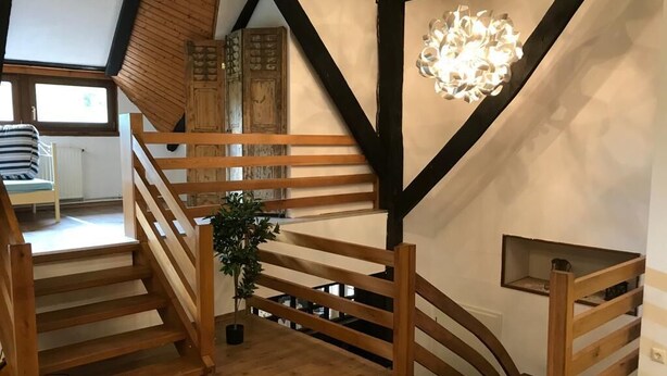 A wooden staircase with a plant in the middle, leading to a second floor. - Gut Strackholt - Apartment "Seemannsgarn" (Großefehn)