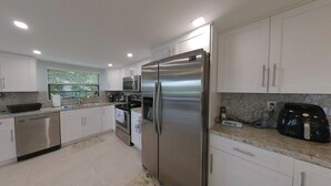 Una cocina moderna con armarios blancos, electrodomésticos de acero inoxidable y encimera de granito.