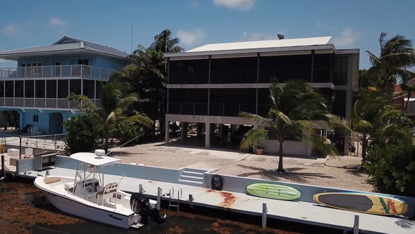 A beachfront property with a boat dock, a covered area with a pool, and a building with multiple balconies. - Huge Ocean Side 2/2 with plenty of Dock Space available for rent! (Key Largo)