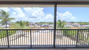 Un balcón con vista a un puerto deportivo, palmeras y edificios.