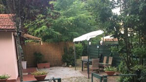 Ein Patio mit Tisch und Stühlen, umgeben von Blumentöpfen und einem Holzzaun.