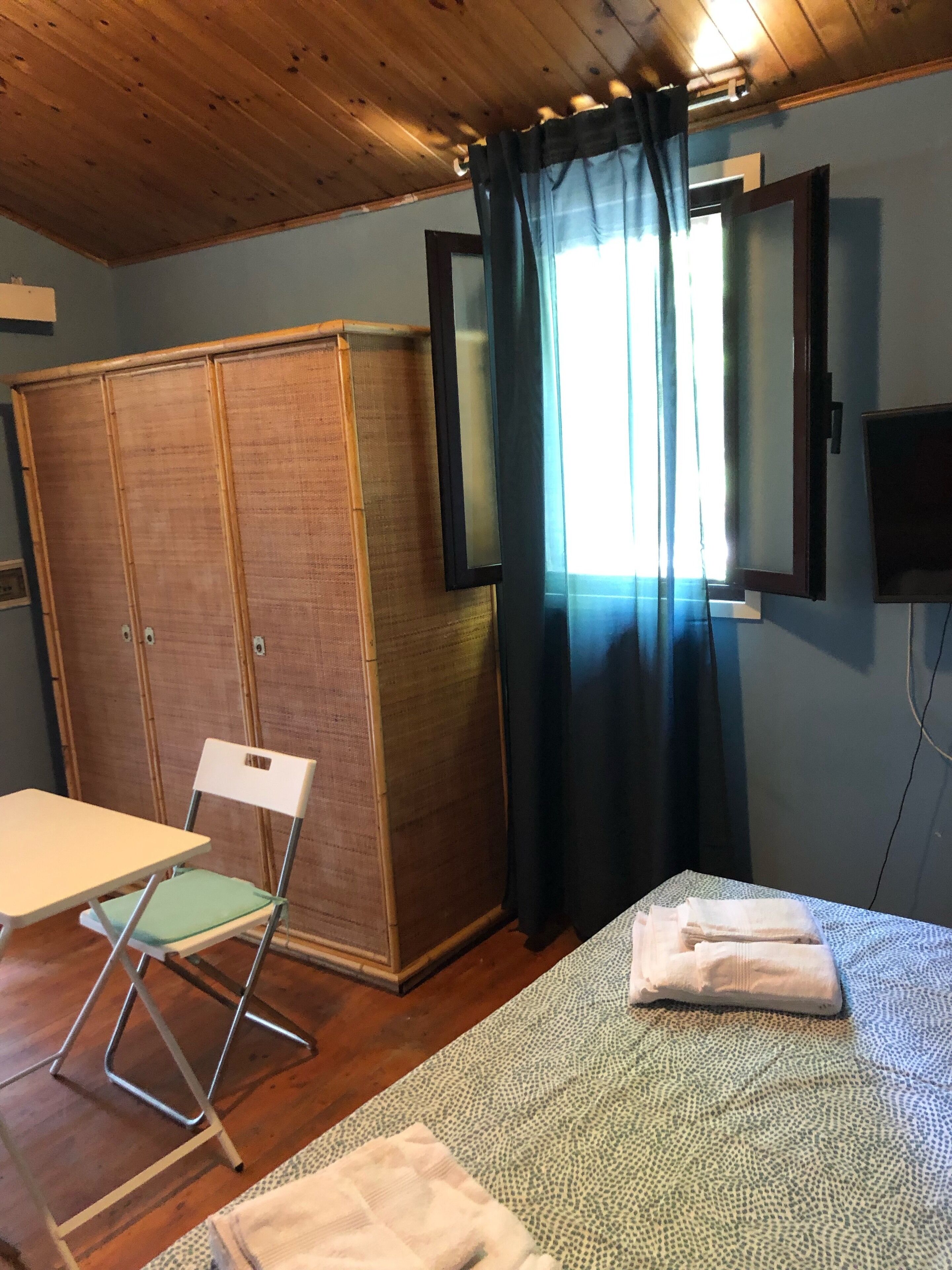Ein Zimmer mit einem Bett, einem Sessel, einem Kleiderschrank und einem Fernseher.