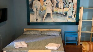 Ein Zimmer mit einem Bett, einem Tisch, zwei Stühlen, einem Bild an der Wand und einer Holzbalkendecke.