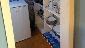 Eine kleine Küche mit einem weißen Kühlschrank, einer Holzzahl und einer gemusterten Spritzschutzwand.