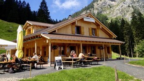 Un edificio in legno con un cartello che riporta la scritta "zumbühli holzbau" e una zona esterna con tavoli e sedie.