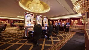 Un casinò con diverse slot machine, un lampadario sontuoso e una moquette decorata.