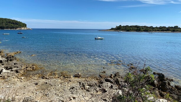 Un paisaje costero con costas rocosas, agua azul cristalina y barcos.