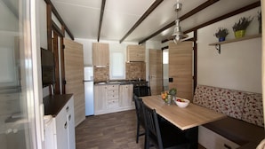 Una cocina compacta con armarios de madera, estufa integrada y un comedor con banco.