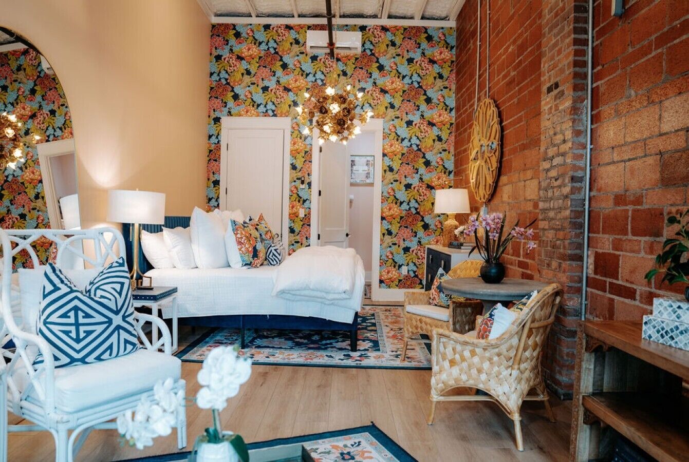A bedroom with a bed, two chairs, a table, and a decorative wall.